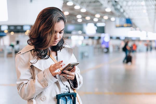 Woman Looking at Phone in Airport