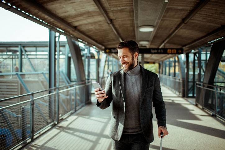 Man Walking with Phone and Luggage