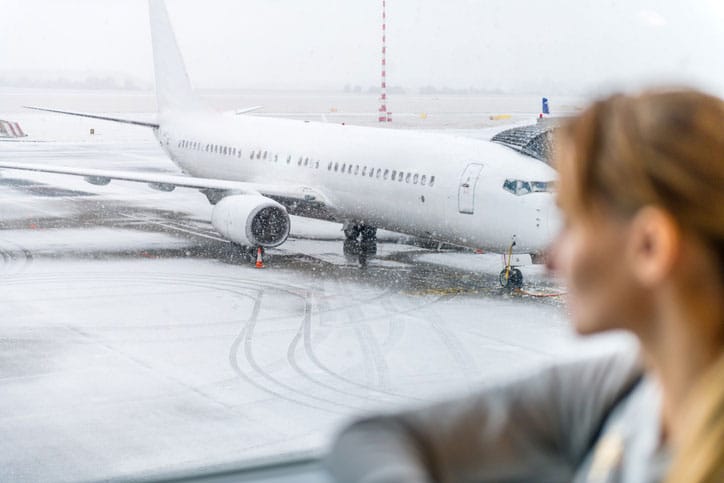 Woman Looking At Snow Covered Airplane
